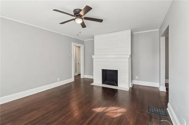 a view of a livingroom with a fireplace a ceiling fan and wooden floor