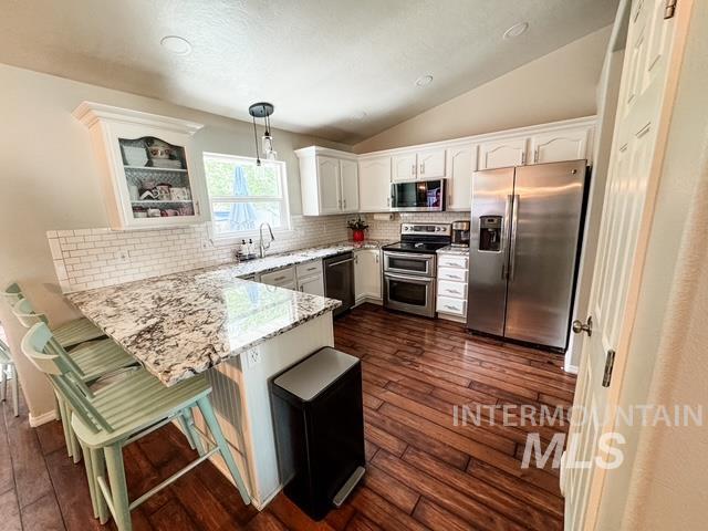 808 O'Leary Way Twin Falls, ID 83301 - Photo 14 of 37 Contemporary kitchen featuring a breakfast bar with stone countertops, white subway tile backsplash, white cabinetry, and wood-finish flooring