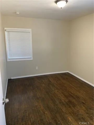 an empty room with wooden floor closet and windows