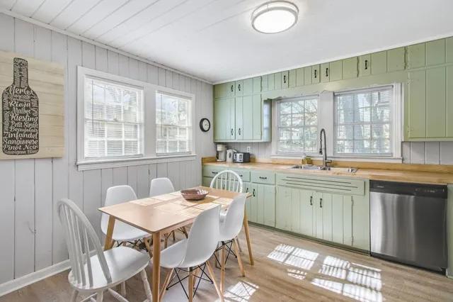 a dining hall with stainless steel appliances granite countertop a sink a stove a table and chairs