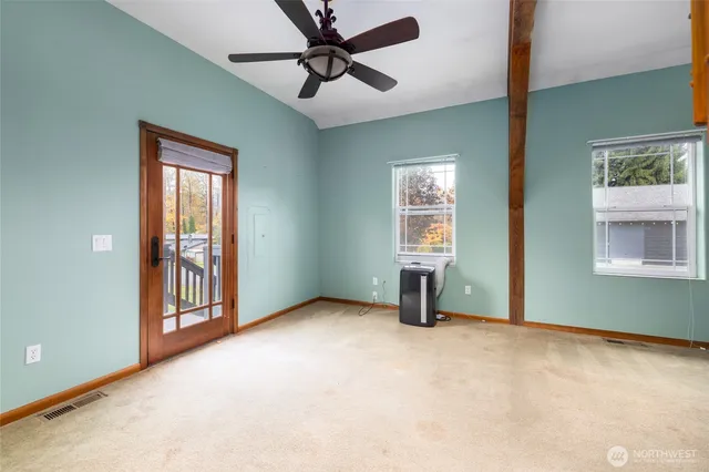 an empty room with windows and fan
