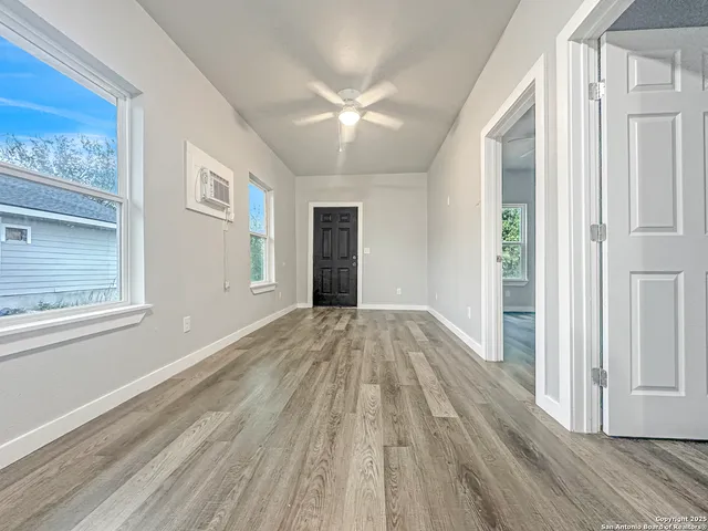 a view of an empty room with wooden floor and a window