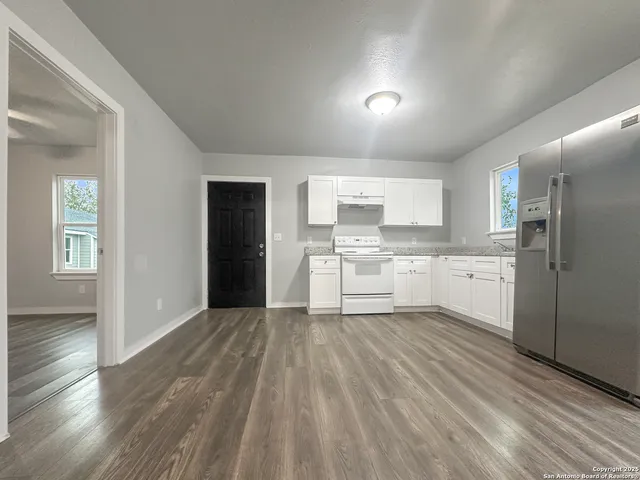 a view of a kitchen with white cabinets and wooden floor