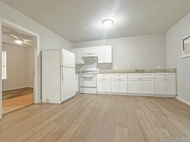 a large white kitchen with wooden floor
