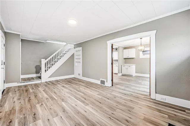 a view of an empty room with wooden floor and stairs