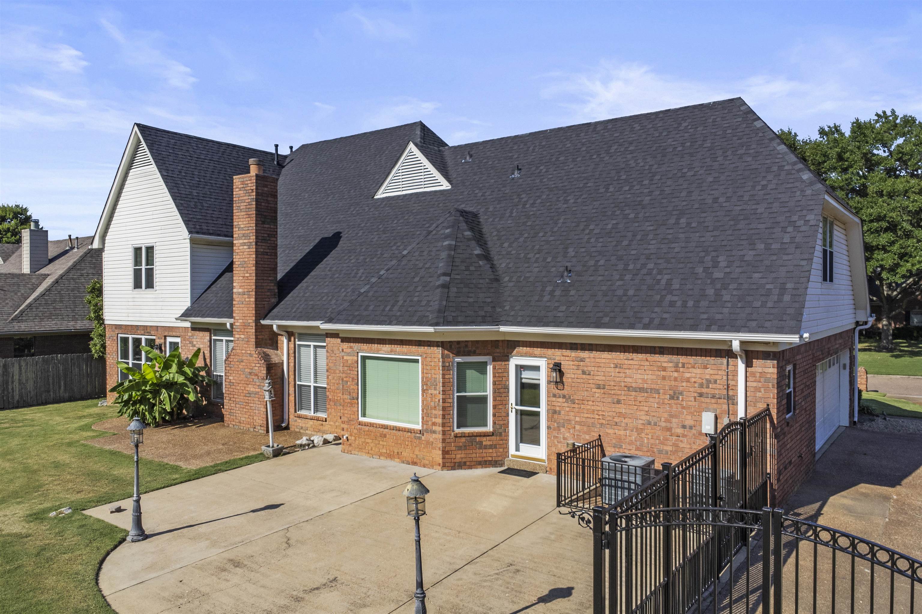 4279 High Plains Road Bartlett, TN 38135 - Photo 30 of 37 Expansive paved patio area featuring a brick exterior, gabled rooflines, and a two-car garage