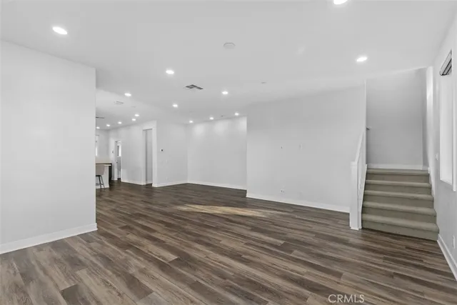a view of an empty room with wooden floor and a ceiling fan