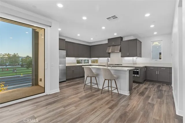a kitchen with stainless steel appliances kitchen island granite countertop a sink cabinets and wooden floor