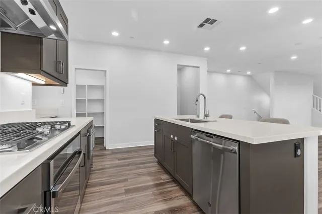 a kitchen with stainless steel appliances granite countertop a sink a stove and a wooden floors