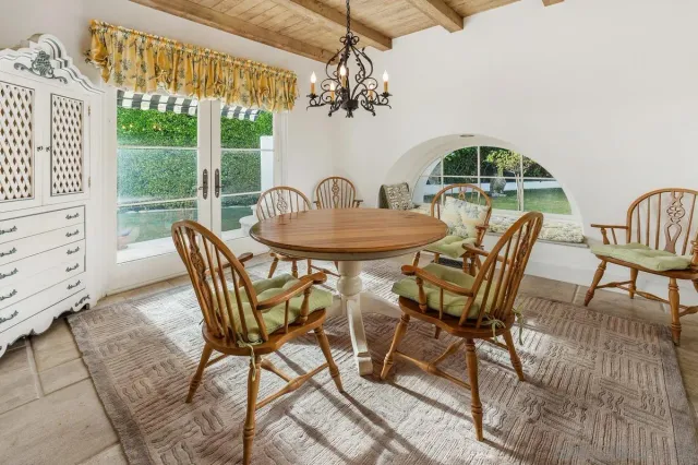 a view of a dining room with furniture a chandelier and large windows