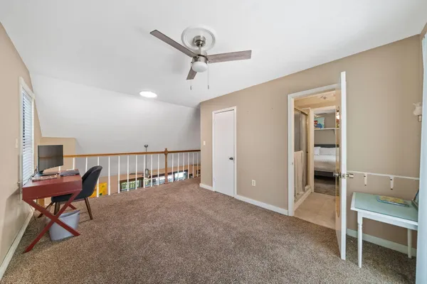 a view of a hallway with furniture and a ceiling fan