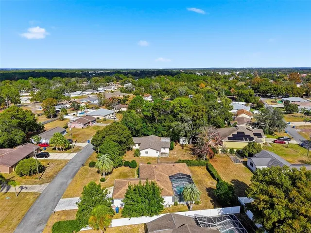an aerial view of residential houses with outdoor space and trees