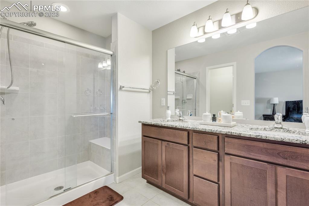2118 Birmingham Loop Colorado Springs, CO 80910 - Photo 16 of 28 a bathroom with a granite countertop sink a mirror and a shower