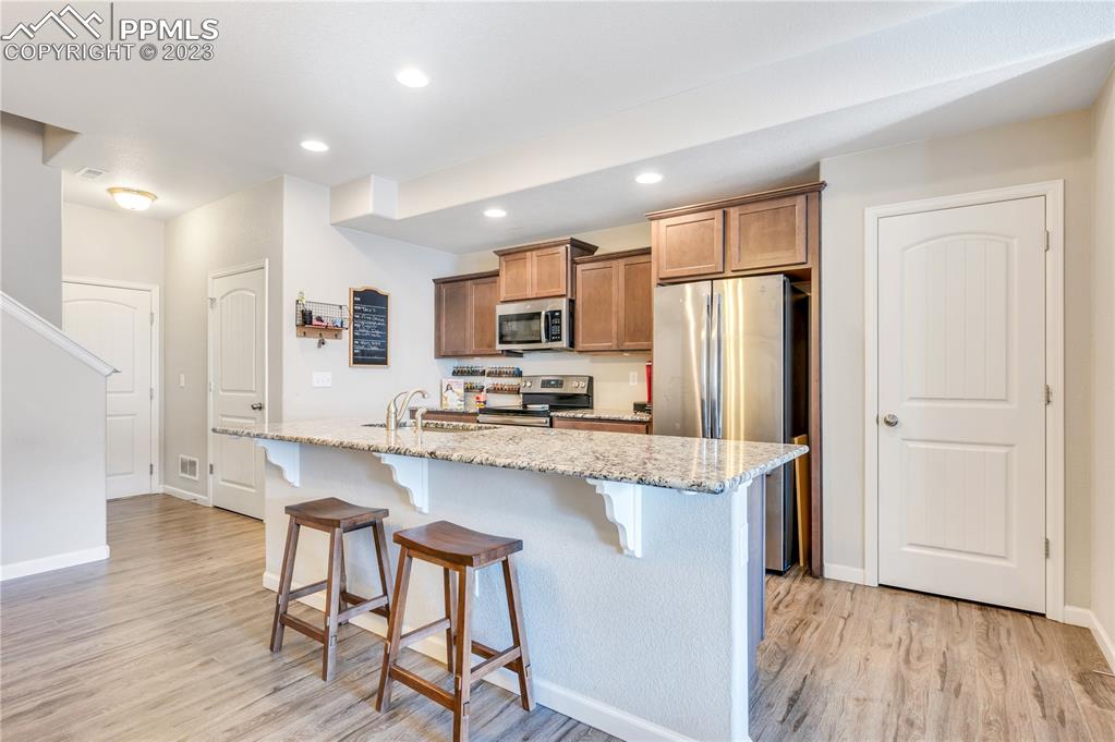 2118 Birmingham Loop Colorado Springs, CO 80910 - Photo 7 of 28 a kitchen with stainless steel appliances granite countertop a refrigerator a stove top oven a sink dishwasher and a dining table with wooden floor