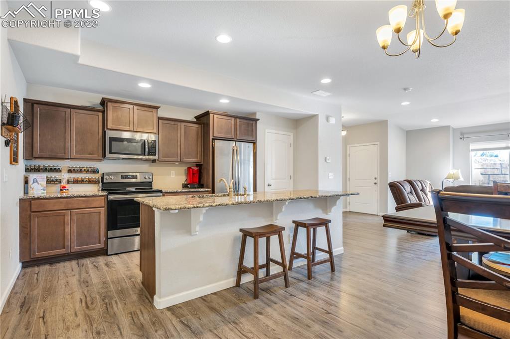 2118 Birmingham Loop Colorado Springs, CO 80910 - Photo 8 of 28 a kitchen with stainless steel appliances granite countertop a stove top oven a sink a dining table and chairs with wooden floor