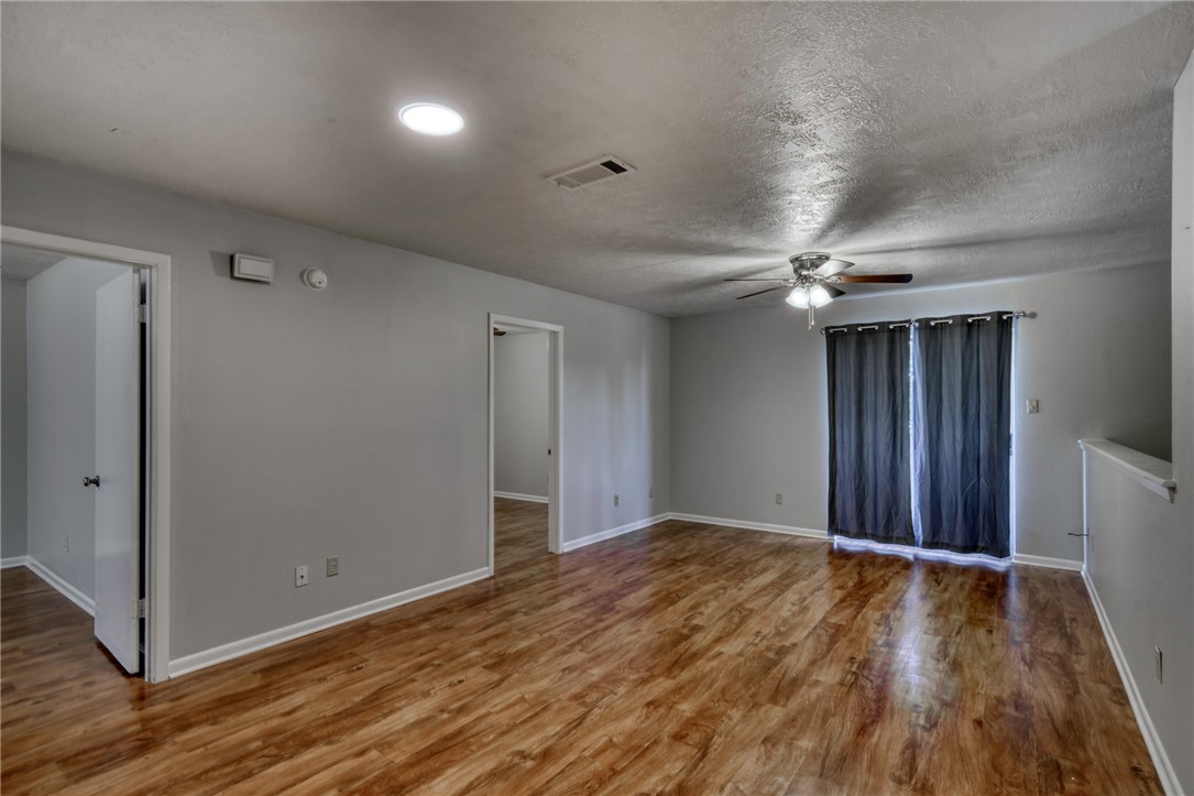 910 Spring Loop, Unit B College Station, TX 77840 - Photo 3 of 10 Empty room with wood finished floors, ceiling fan, and a textured ceiling