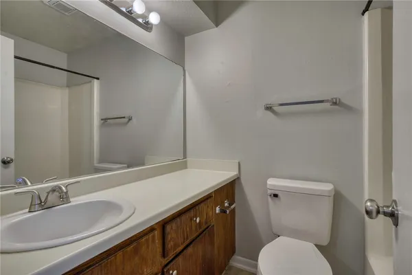 a bathroom with a granite countertop toilet sink and mirror