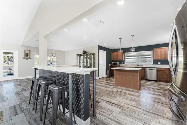 a open kitchen with kitchen island a stove a sink dishwasher and a refrigerator with wooden floor