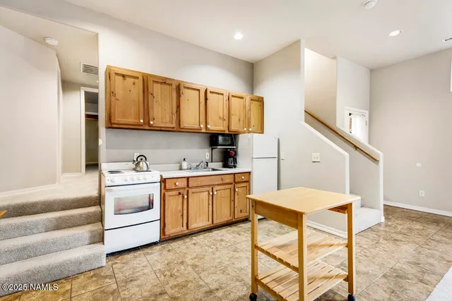 a kitchen with stainless steel appliances granite countertop a stove a sink dishwasher and a refrigerator with white cabinets