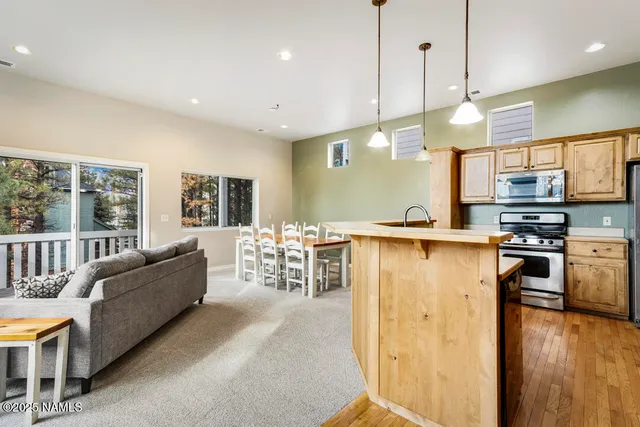 a living room with stainless steel appliances granite countertop a couch a rug a fireplace and a large window