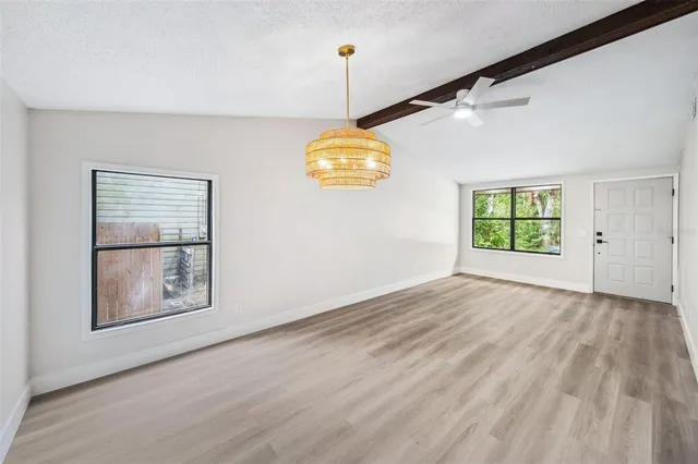 a view of an empty room with window and wooden floor