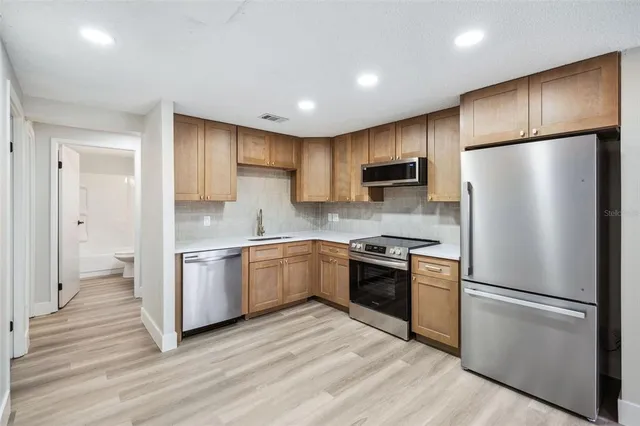 a kitchen with a refrigerator a stove top oven and wooden floor