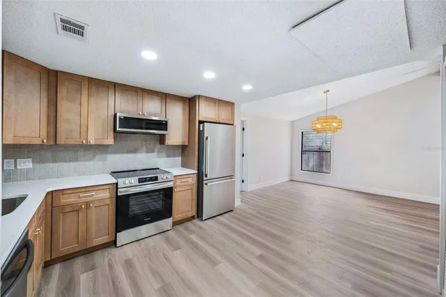 a kitchen with stainless steel appliances granite countertop a stove a sink and a refrigerator