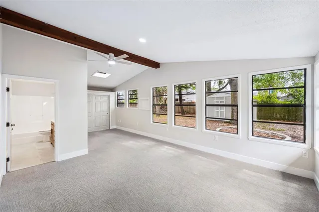 a view of an empty room with a window and kitchen view