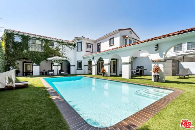 a view of pool with lawn chairs and large trees