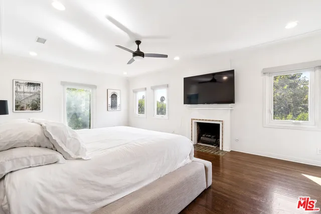 a spacious bedroom with a large bed a flat tv screen and a fireplace