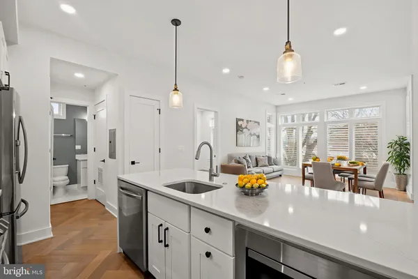 a kitchen with stainless steel appliances a sink a counter top space and living room view