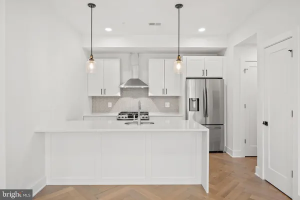 a kitchen with stainless steel appliances a refrigerator a stove a sink and a fireplace