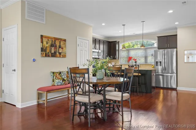 a kitchen with stainless steel appliances granite countertop a stove top oven a sink dishwasher a dining table and chairs with wooden floor