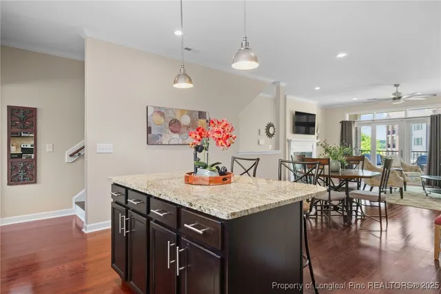 a kitchen with stainless steel appliances granite countertop a refrigerator a stove a sink dishwasher a dining table and chairs with wooden floor