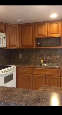 a kitchen with granite countertop a stove a sink and a microwave