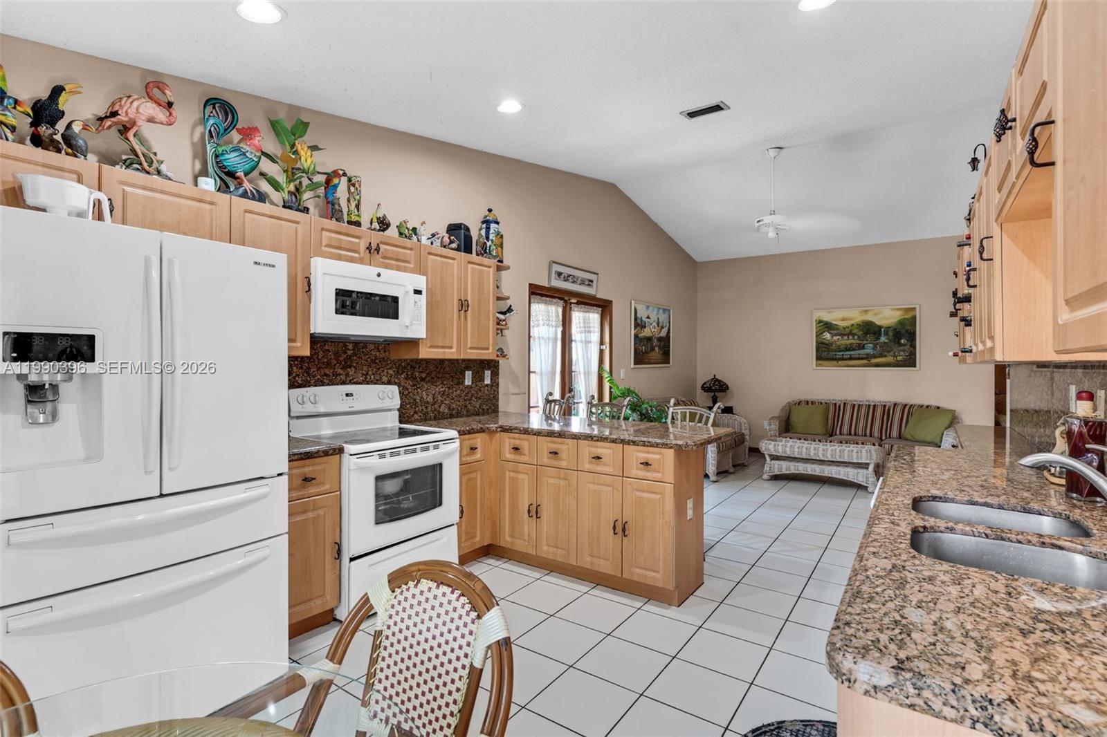15012 Southwest 45th Lane Miami, FL 33185 - Photo 13 of 43 a kitchen with stainless steel appliances granite countertop a refrigerator sink stove and white cabinets