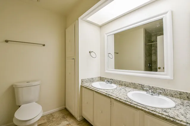 a bathroom with a granite countertop sink toilet and mirror