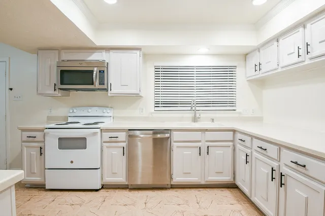 a kitchen with granite countertop white cabinets and white appliances