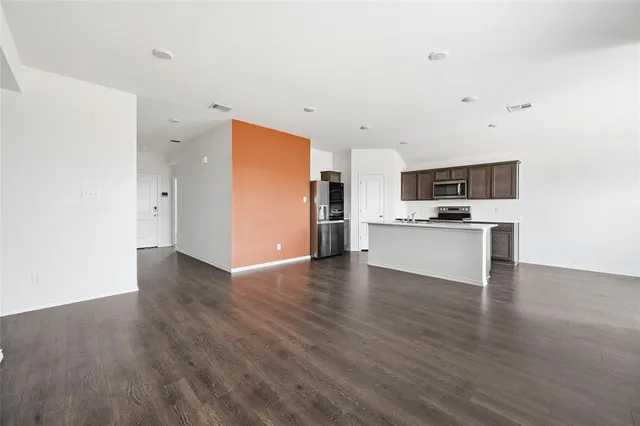 a view of a kitchen with a sink stove cabinets and empty room