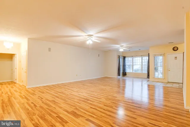 a kitchen with stainless steel appliances granite countertop a stove top oven a sink dishwasher a refrigerator and white cabinets with wooden floor