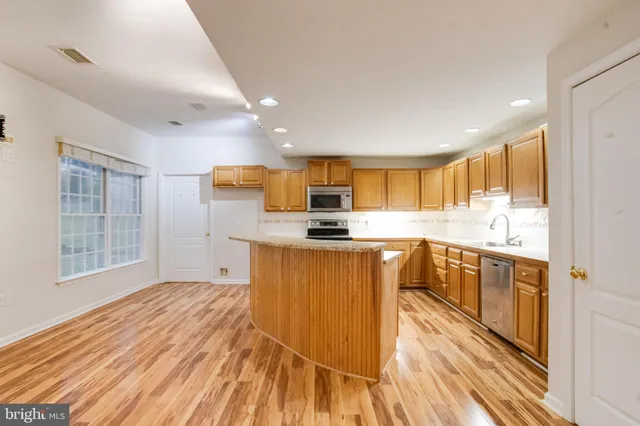 a kitchen with stainless steel appliances granite countertop a sink and cabinets with wooden floor