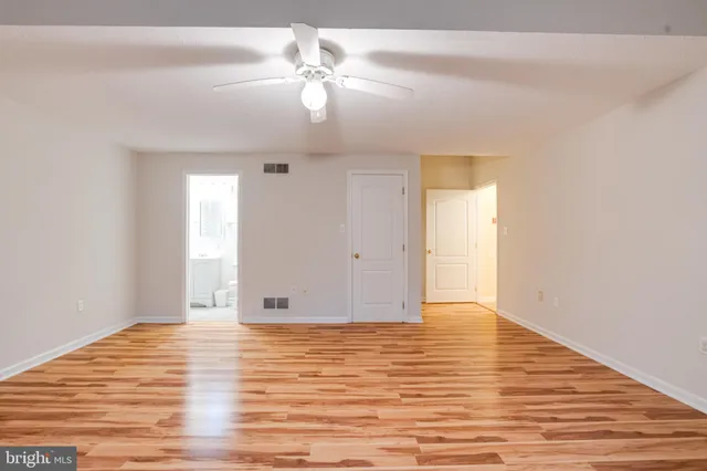 an empty room with wooden floor fan and windows