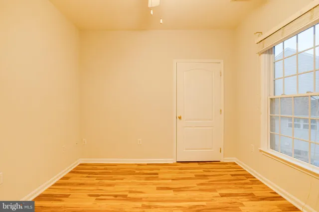 en empty room with windows and chandelier fan