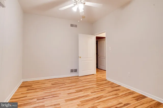 an empty room with a chandelier fan and windows