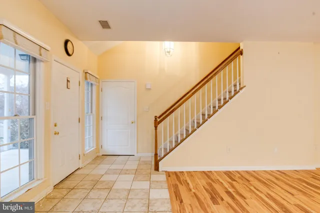 a view of an empty room with chandelier fan and wooden floor