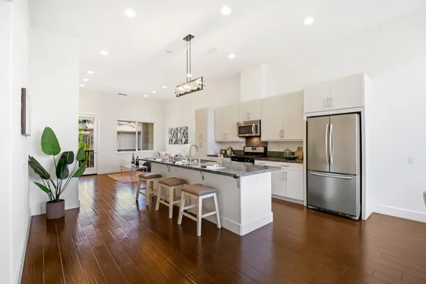 a kitchen with stainless steel appliances granite countertop a refrigerator a stove a sink dishwasher a microwave oven with wooden floor