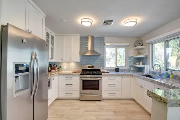 a kitchen with stainless steel appliances granite countertop a stove a refrigerator and a sink