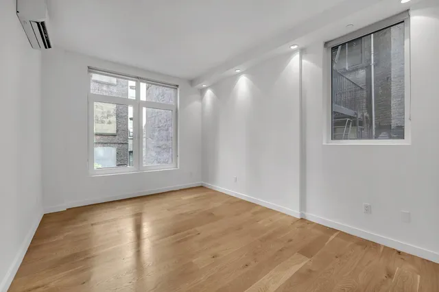 a view of an empty room with window and wooden floor