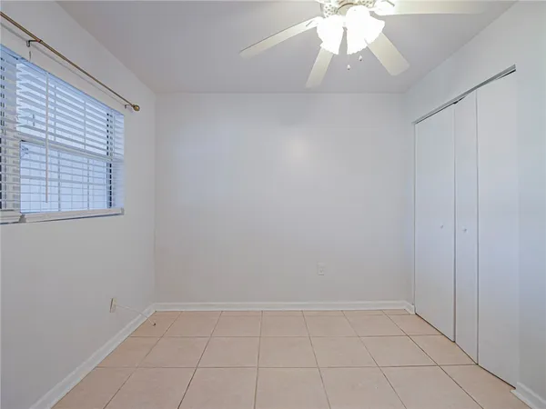 an empty room with a chandelier fan and windows