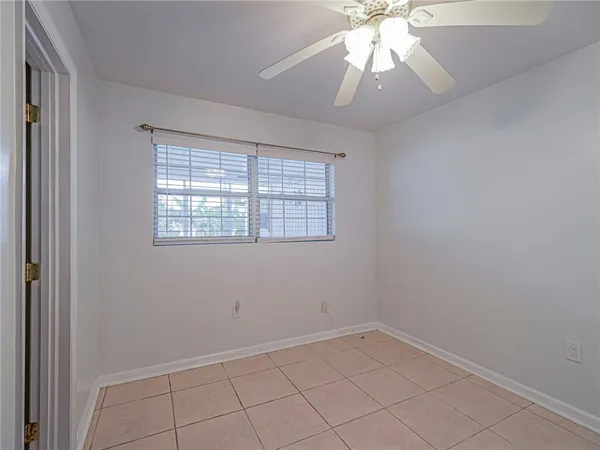 an empty room with a window and a chandelier fan